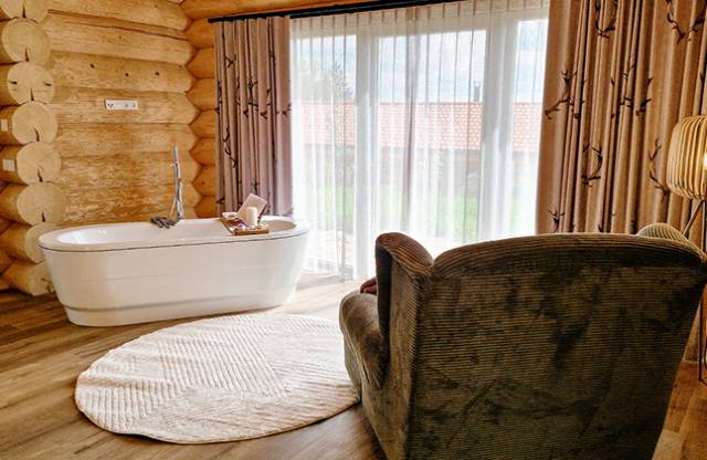 Freistehende Badewanne mit Sessel daneben und Blick ins Freie