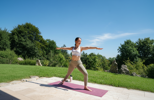Frau macht die Yogapose der Krieger draußen in der Natur